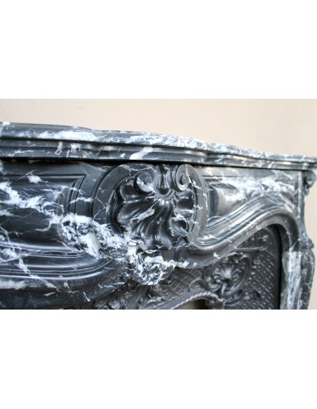 Antique Baroque-style fireplace mantel carved in black Marquinia marble with white veining, with its original cast iron insert.
