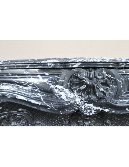 Antique Baroque-style fireplace mantel carved in black Marquinia marble with white veining, with its original cast iron insert.