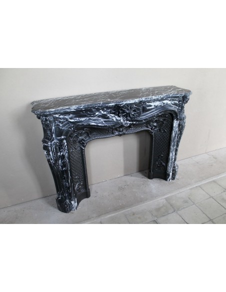 Antique Baroque-style fireplace mantel carved in black Marquinia marble with white veining, with its original cast iron insert.