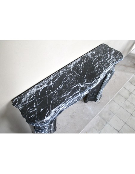 Antique Baroque-style fireplace mantel carved in black Marquinia marble with white veining, with its original cast iron insert.