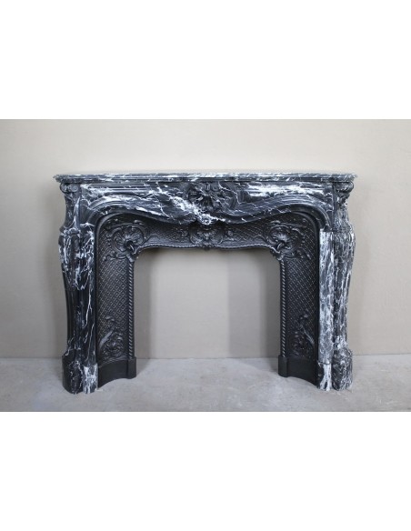 Antique Baroque-style fireplace mantel carved in black Marquinia marble with white veining, with its original cast iron insert.