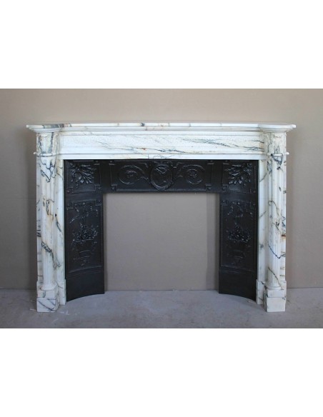 Rare and refined Neoclassical “Macaron” fireplace mantel with floral sculptural elements, perlage detailing, and column motifs.
