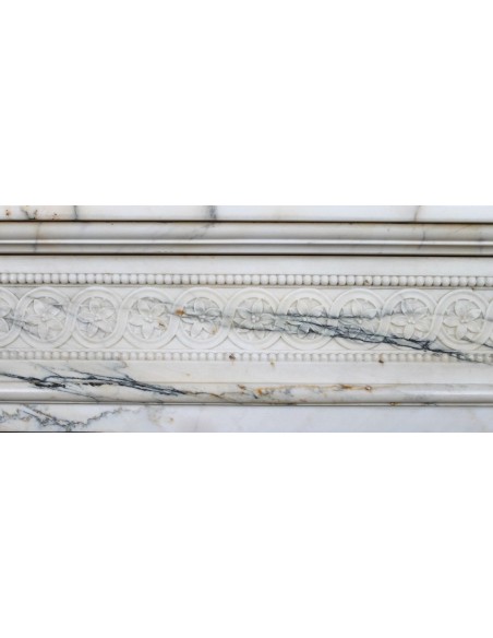 Rare and refined Neoclassical “Macaron” fireplace mantel with floral sculptural elements, perlage detailing, and column motifs.