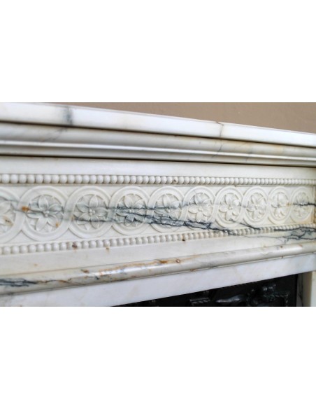 Rare and refined Neoclassical “Macaron” fireplace mantel with floral sculptural elements, perlage detailing, and column motifs.