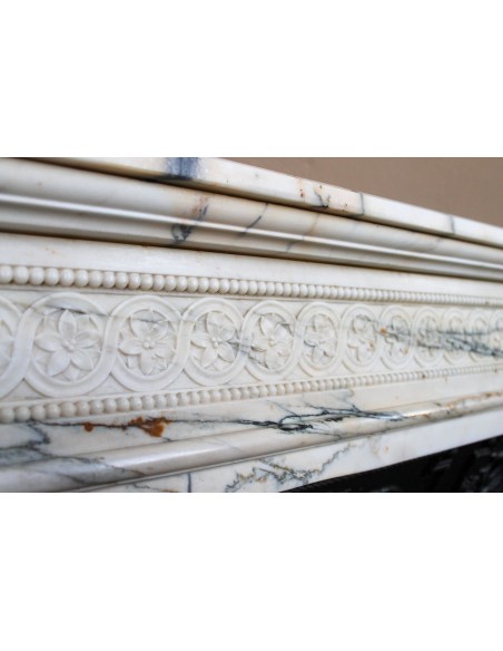 Rare and refined Neoclassical “Macaron” fireplace mantel with floral sculptural elements, perlage detailing, and column motifs.