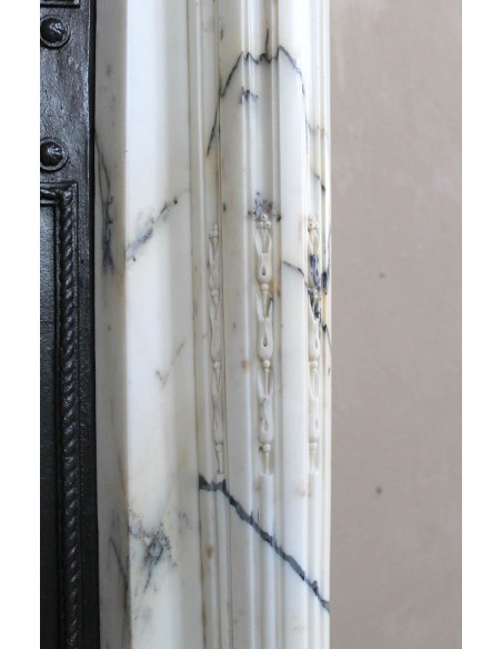 Rare and refined Neoclassical “Macaron” fireplace mantel with floral sculptural elements, perlage detailing, and column motifs.