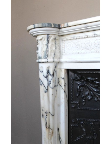 Rare and refined Neoclassical “Macaron” fireplace mantel with floral sculptural elements, perlage detailing, and column motifs.