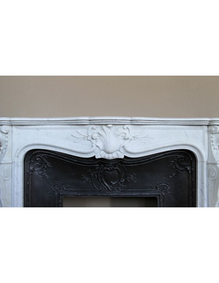 A refined antique white marble mantel in the Baroque style, carved with floral motifs, with its original cast iron insert.