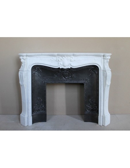 A refined antique white marble mantel in the Baroque style, carved with floral motifs, with its original cast iron insert.