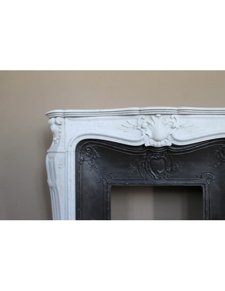 A refined antique white marble mantel in the Baroque style, carved with floral motifs, with its original cast iron insert.
