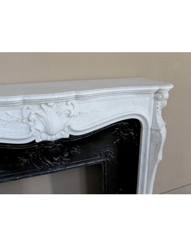 A refined antique white marble mantel in the Baroque style, carved with floral motifs, with its original cast iron insert.