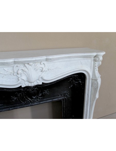 A refined antique white marble mantel in the Baroque style, carved with floral motifs, with its original cast iron insert.