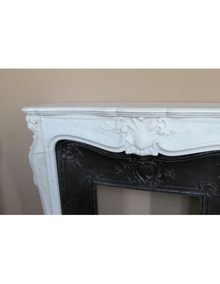 A refined antique white marble mantel in the Baroque style, carved with floral motifs, with its original cast iron insert.