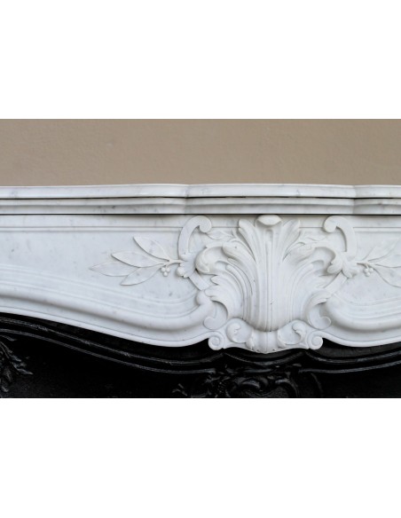 A refined antique white marble mantel in the Baroque style, carved with floral motifs, with its original cast iron insert.