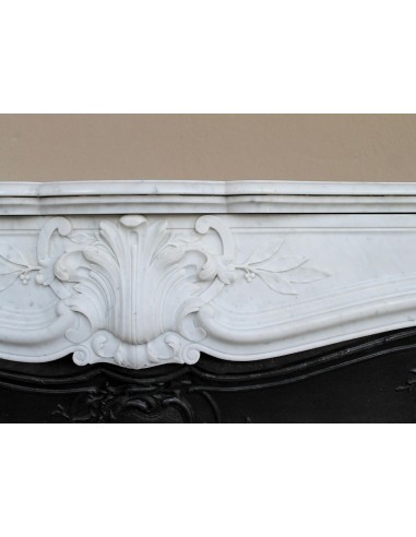 A refined antique white marble mantel in the Baroque style, carved with floral motifs, with its original cast iron insert.