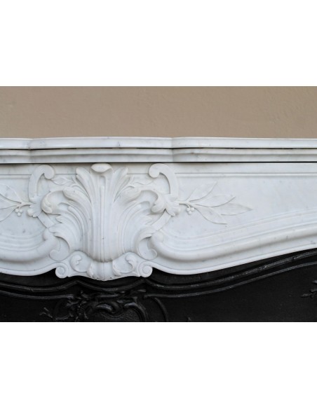 A refined antique white marble mantel in the Baroque style, carved with floral motifs, with its original cast iron insert.