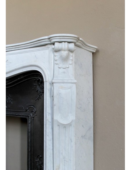 A refined antique white marble mantel in the Baroque style, carved with floral motifs, with its original cast iron insert.