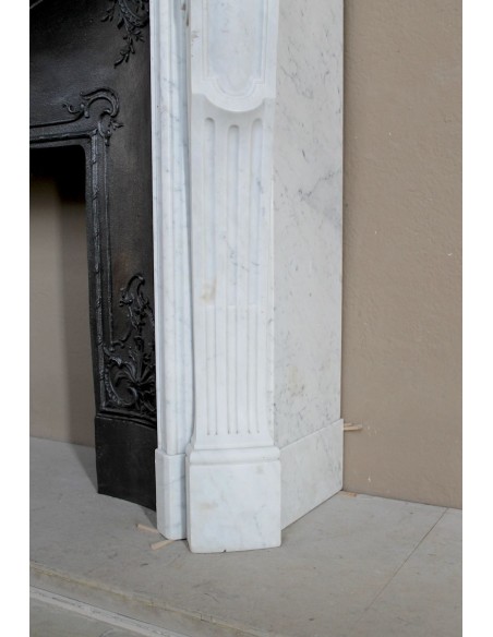 A refined antique white marble mantel in the Baroque style, carved with floral motifs, with its original cast iron insert.