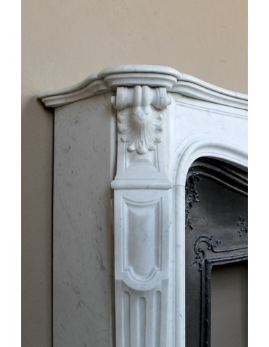 A refined antique white marble mantel in the Baroque style, carved with floral motifs, with its original cast iron insert.
