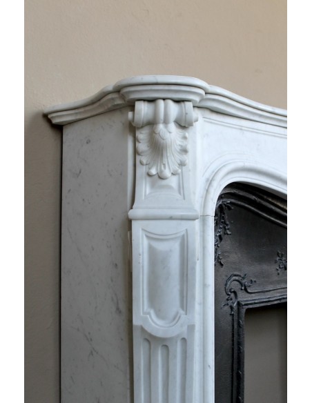A refined antique white marble mantel in the Baroque style, carved with floral motifs, with its original cast iron insert.