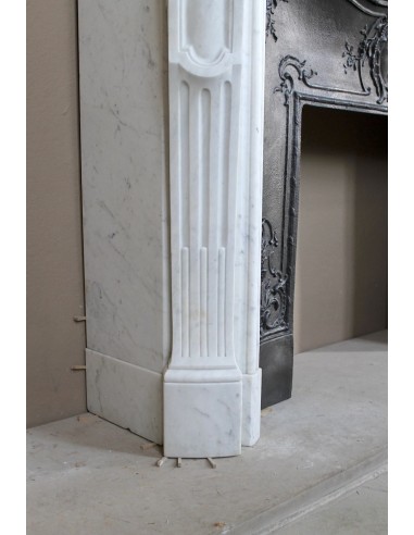 A refined antique white marble mantel in the Baroque style, carved with floral motifs, with its original cast iron insert.