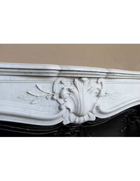 A refined antique white marble mantel in the Baroque style, carved with floral motifs, with its original cast iron insert.