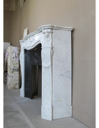 A refined antique white marble mantel in the Baroque style, carved with floral motifs, with its original cast iron insert.
