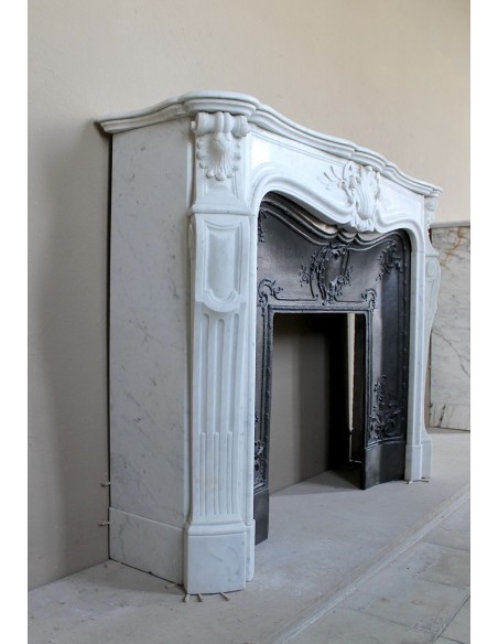 A refined antique white marble mantel in the Baroque style, carved with floral motifs, with its original cast iron insert.