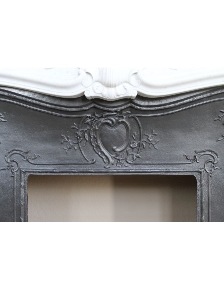 A refined antique white marble mantel in the Baroque style, carved with floral motifs, with its original cast iron insert.