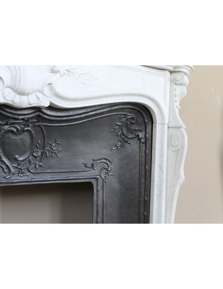 A refined antique white marble mantel in the Baroque style, carved with floral motifs, with its original cast iron insert.