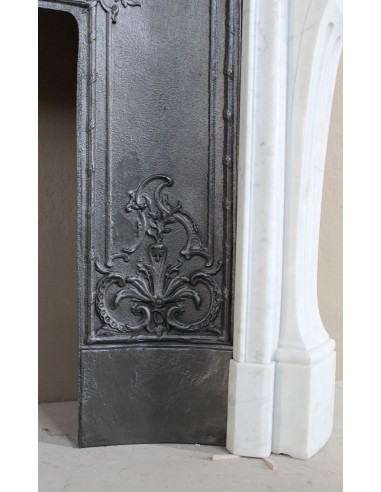 A refined antique white marble mantel in the Baroque style, carved with floral motifs, with its original cast iron insert.