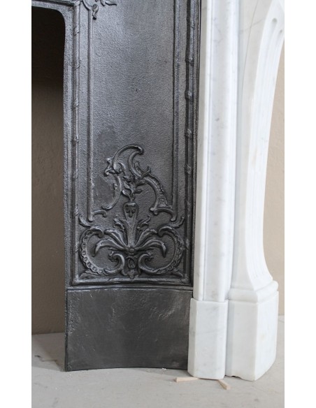 A refined antique white marble mantel in the Baroque style, carved with floral motifs, with its original cast iron insert.