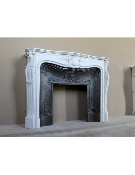 A refined antique white marble mantel in the Baroque style, carved with floral motifs, with its original cast iron insert.