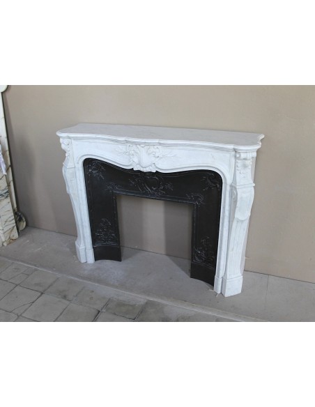 A refined antique white marble mantel in the Baroque style, carved with floral motifs, with its original cast iron insert.