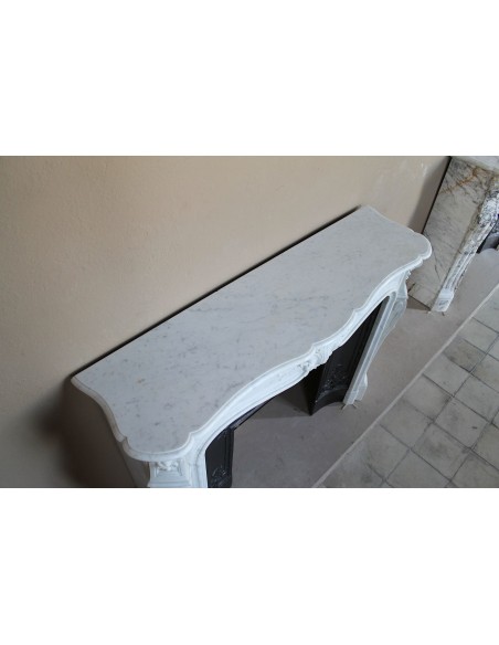 A refined antique white marble mantel in the Baroque style, carved with floral motifs, with its original cast iron insert.