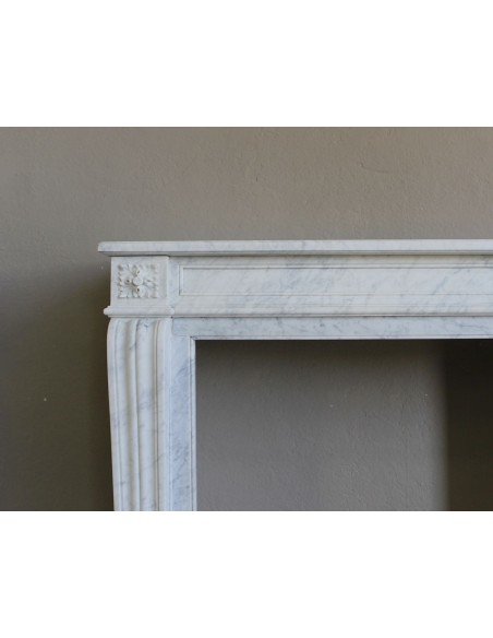 Small and well-proportioned Neoclassical fireplace with curved shoulders in white marble, an elegant and refined fire surround.