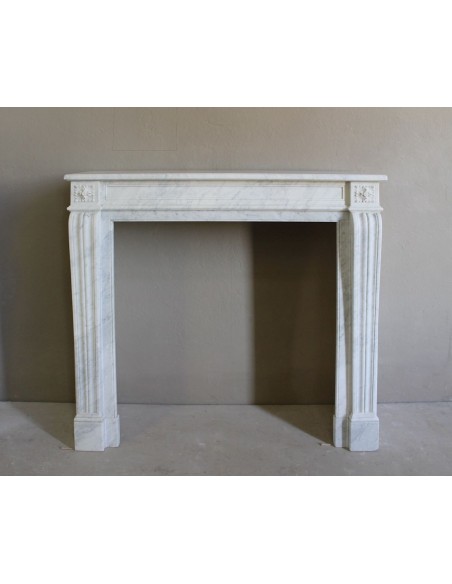 Small and well-proportioned Neoclassical fireplace with curved shoulders in white marble, an elegant and refined fire surround.