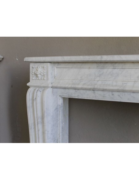 Small and well-proportioned Neoclassical fireplace with curved shoulders in white marble, an elegant and refined fire surround.