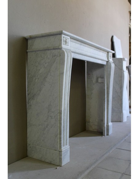 Small and well-proportioned Neoclassical fireplace with curved shoulders in white marble, an elegant and refined fire surround.