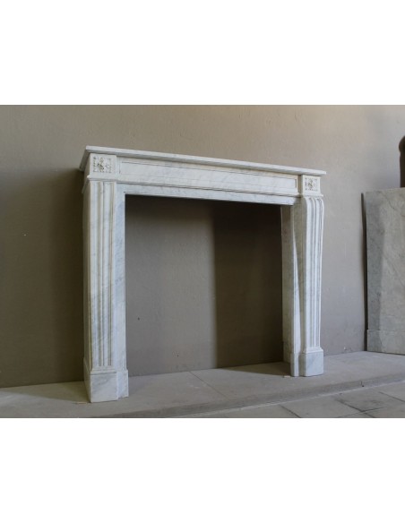 Small and well-proportioned Neoclassical fireplace with curved shoulders in white marble, an elegant and refined fire surround.