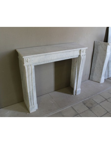 Small and well-proportioned Neoclassical fireplace with curved shoulders in white marble, an elegant and refined fire surround.