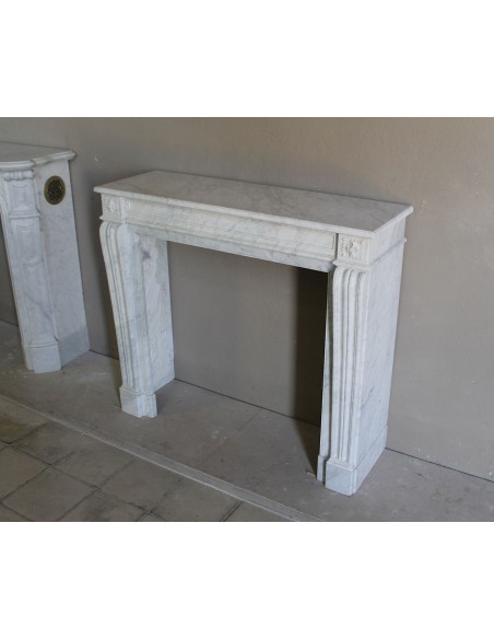Small and well-proportioned Neoclassical fireplace with curved shoulders in white marble, an elegant and refined fire surround.