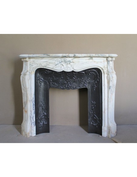An antique refined Louis XV “Coquille” fireplace mantel in Calacatta Gold marble with its original floral cast-iron insert.