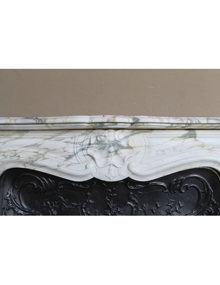 An antique refined Louis XV “Coquille” fireplace mantel in Calacatta Gold marble with its original floral cast-iron insert.
