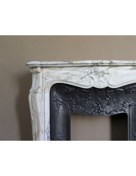 An antique refined Louis XV “Coquille” fireplace mantel in Calacatta Gold marble with its original floral cast-iron insert.