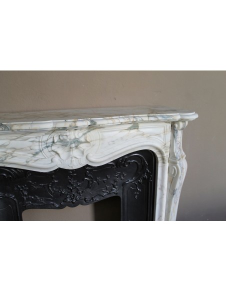 An antique refined Louis XV “Coquille” fireplace mantel in Calacatta Gold marble with its original floral cast-iron insert.