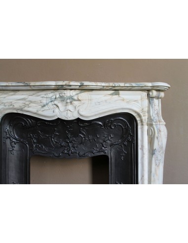 An antique refined Louis XV “Coquille” fireplace mantel in Calacatta Gold marble with its original floral cast-iron insert.