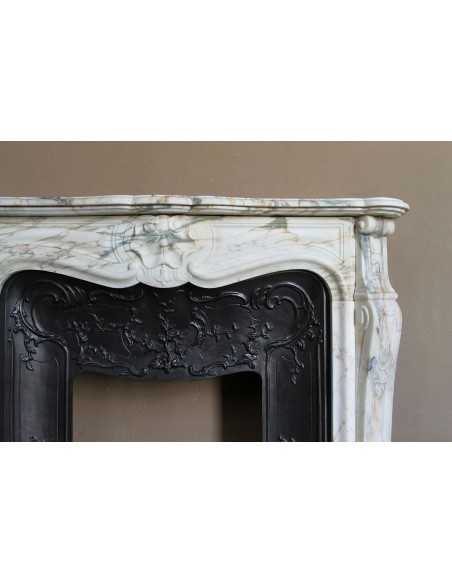 An antique refined Louis XV “Coquille” fireplace mantel in Calacatta Gold marble with its original floral cast-iron insert.