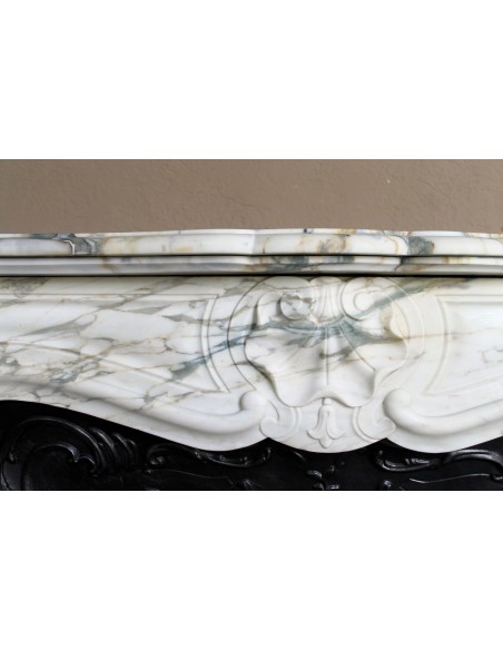 An antique refined Louis XV “Coquille” fireplace mantel in Calacatta Gold marble with its original floral cast-iron insert.