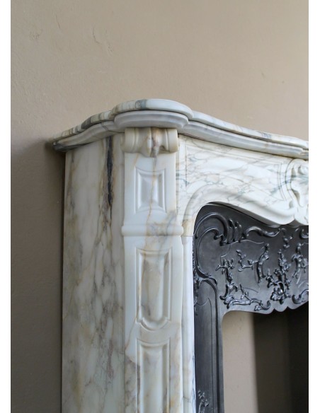 An antique refined Louis XV “Coquille” fireplace mantel in Calacatta Gold marble with its original floral cast-iron insert.